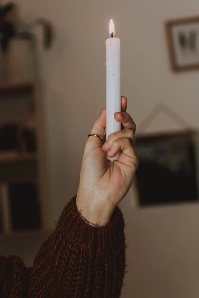 Hand holding lit white candle